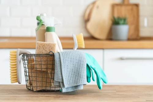 A basket of cleaning supplies sitting on the counter.