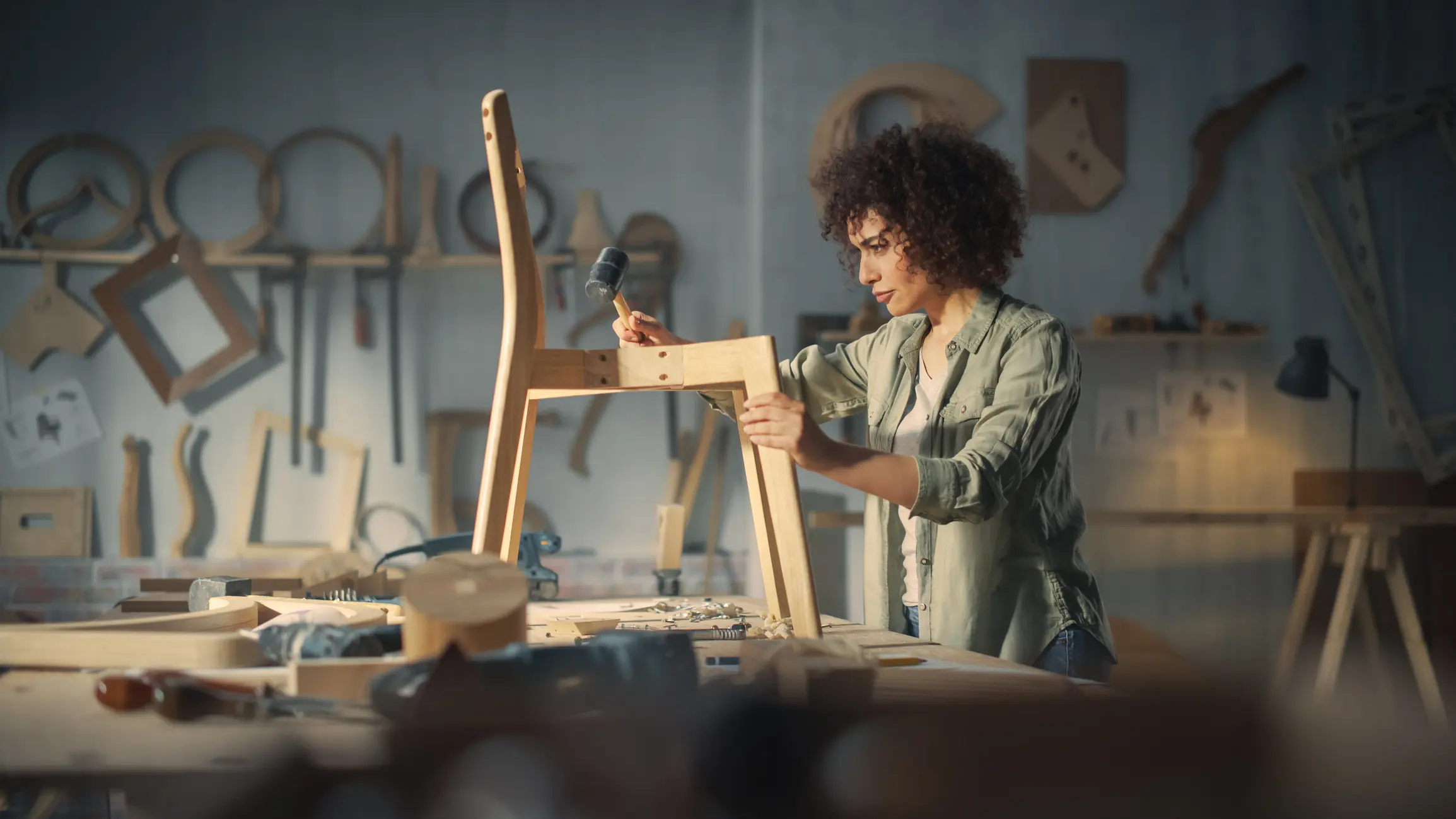 Talented Female Furniture Designer Working in a Workshop in a Creative Loft Space with Tools and Equipment.